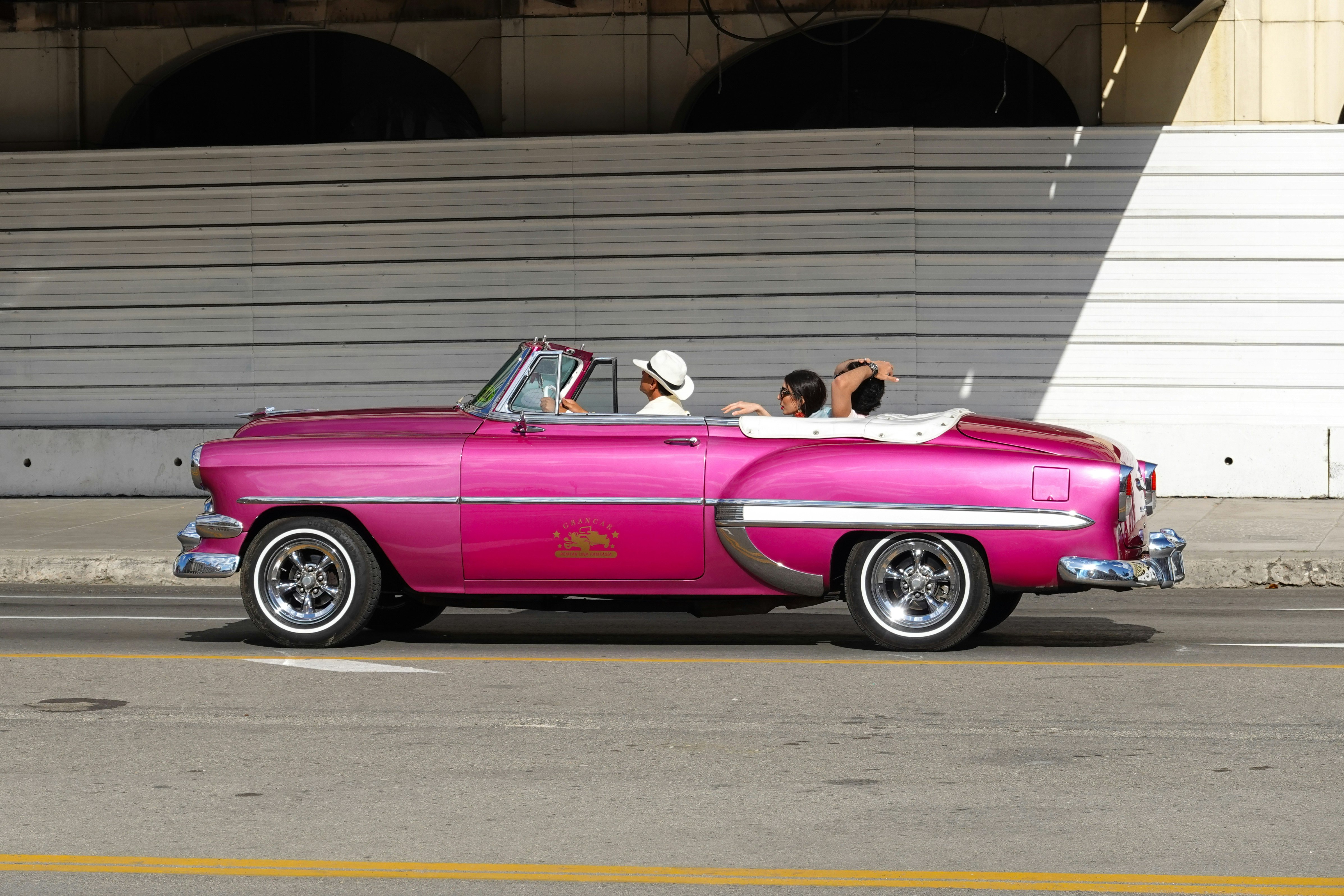 pink convertible car parked in front of white building